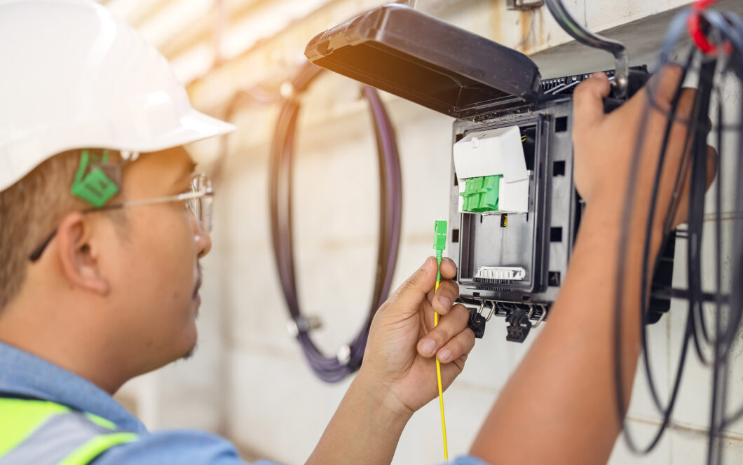 An internet technician is repairing or maintaining a fiber optic connection by opening a fiber optic connector.
