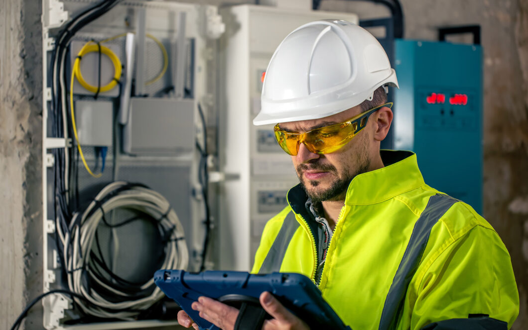 Man, an electrical technician working in a switchboard with fuses. Installation and connection of electrical equipment.